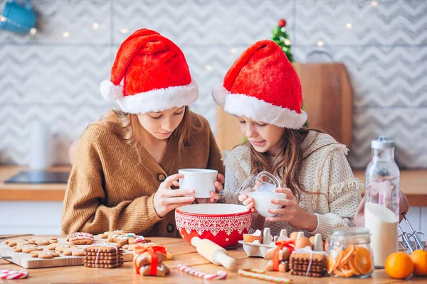 Kleine Mädchen basteln Weihnachts-Lebkuchenhaus am Kamin im geschmückten Wohnzimmer. — Stockfoto