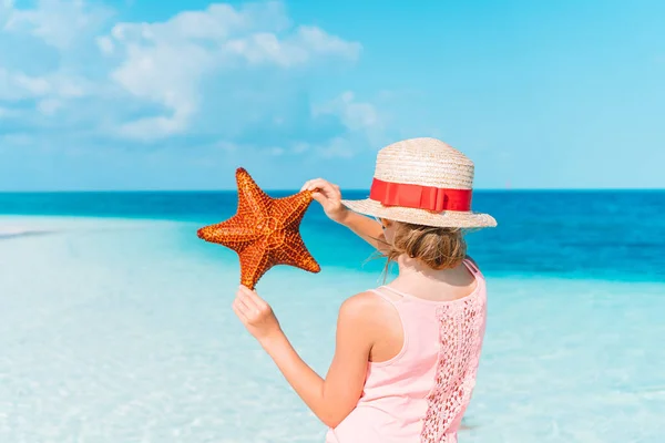 Adorabile bambina con stelle marine sulla spiaggia bianca e vuota — Foto Stock