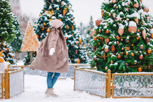 Gelukkig meisje in de buurt van dennenboom tak in de sneeuw voor het nieuwe jaar. — Stockfoto