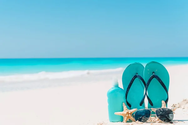 Bottiglie di crema solare, occhiali, stelle marine e occhiali da sole su sfondo spiaggia di sabbia bianca oceano — Foto Stock