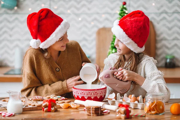 Маленькие девочки делают рождественский пряничный домик у камина в украшенной гостиной. — стоковое фото