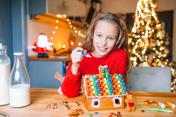 Dziewczynka robi świąteczny domek z piernika w kuchni — Zdjęcie stockowe