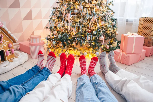 Foto de cerca de los pies de la familia en calcetines de lana junto al árbol de Navidad — Foto de Stock