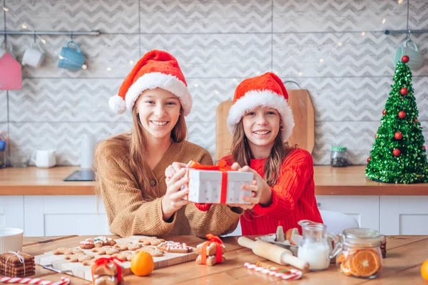 Niñas haciendo casa de jengibre de Navidad en la chimenea en la sala de estar decorada. —  Fotos de Stock