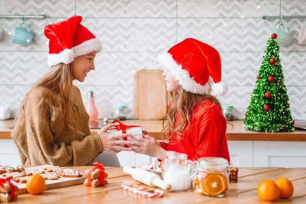 Meisjes maken kerst peperkoek huis bij open haard in ingerichte woonkamer. — Stockfoto