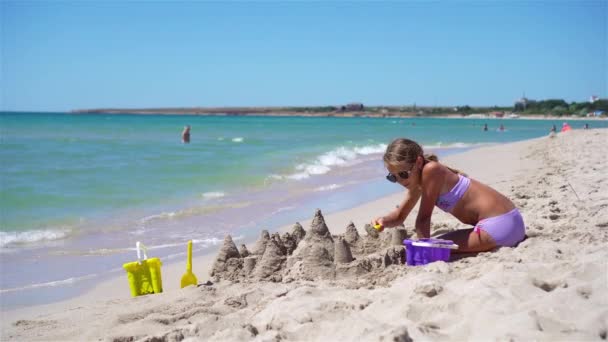 Gadis kecil di pantai putih tropis membuat istana pasir — Stok Video