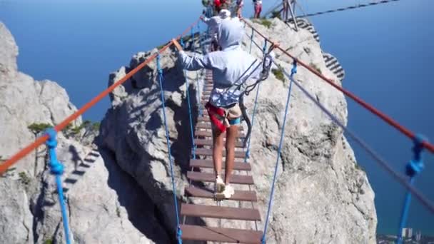 Girls crossing the chasm on the rope bridge. Black sea background, Crimea — Stock Video