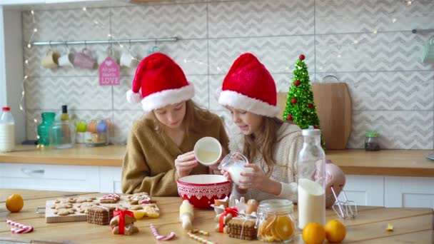 Niñas haciendo casa de jengibre de Navidad en la chimenea en la sala de estar decorada. — Vídeos de Stock