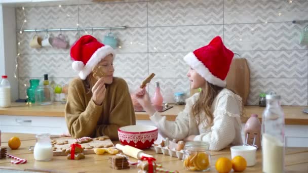 Små flickor gör jul pepparkakshus vid öppen spis i dekorerat vardagsrum. — Stockvideo