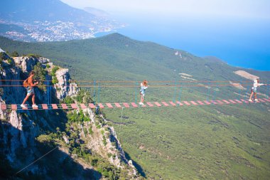 Cesur baba ve çocuklardan oluşan aile deniz ve dağların arkasında asma köprüde.