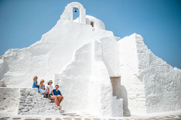 Семейный отдых в Европе. Родители и дети на улице типичной греческой традиционной деревни с белыми стенами и красочными дверями на острове Миконос — стоковое фото