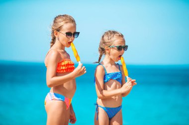 Plaj tatili sırasında dondurma yiyen mutlu küçük kızlar. İnsanlar, çocuklar, arkadaşlar ve arkadaşlık kavramı