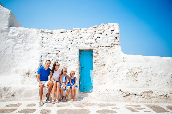 Family vacation in Europe. Parents and kids at street of typical greek traditional village with white walls and colorful doors on Mykonos Island — Stock Photo, Image