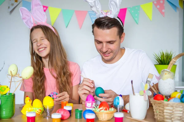 Ojciec i jego córeczka malują jajka. Szczęśliwa rodzina przygotowuje się do Wielkanocy. — Zdjęcie stockowe