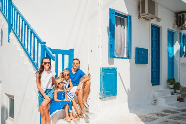 Family vacation in Europe. Parents and kids at street of typical greek traditional village with white walls and colorful doors on Mykonos Island — Stock Photo, Image