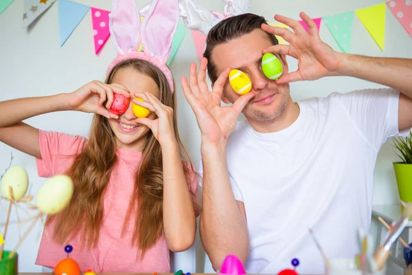 Vater und seine kleine Tochter bemalen Eier. Glückliche Familie bereitet sich auf Ostern vor. — Stockfoto