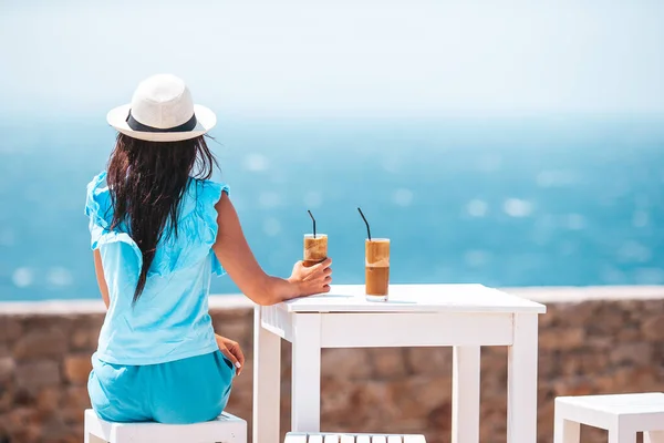 Mujer joven bebiendo café frío disfrutando de vistas al mar — Foto de Stock