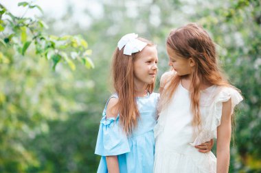 Bahar günü çiçek açan elma bahçesinde sevimli küçük kızlar.