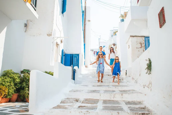 Семейный отдых в Европе. Родители и дети на улице типичной греческой традиционной деревни с белыми стенами и красочными дверями на острове Миконос — стоковое фото