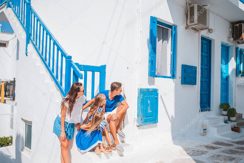 Parents and kids at street of typical greek traditional village on Mykonos Island, in Greece