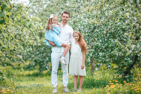 Schattige familie in bloeiende kersentuin op mooie lentedag — Stockfoto