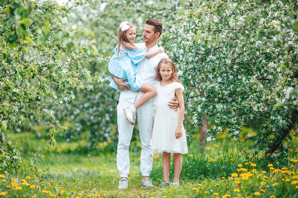 Adorável família no jardim florescendo cereja no belo dia de primavera — Fotografia de Stock