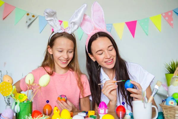 Mutter und ihre kleine Tochter bemalen Eier. Glückliche Familie bereitet sich auf Ostern vor. — Stockfoto