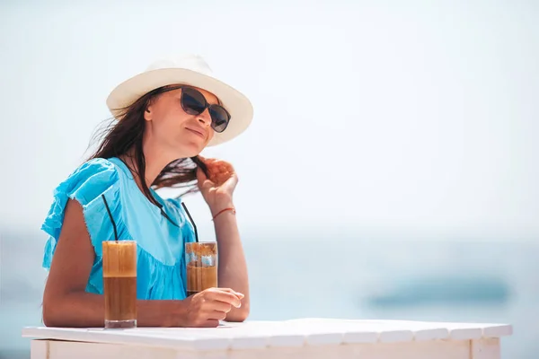 Junge Frau trinkt kalten Kaffee und genießt Meerblick — Stockfoto