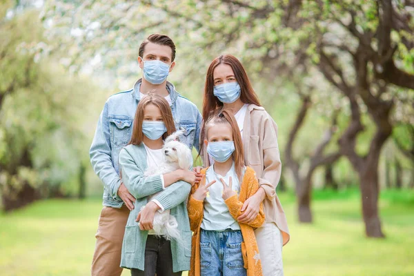 Adorable family in blooming cherry garden in masks