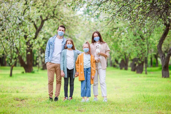 Entzückende Familie im blühenden Kirschgarten in Masken — Stockfoto