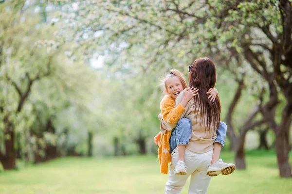 Familj till mor och dotter i blommande körsbärsträdgård — Stockfoto