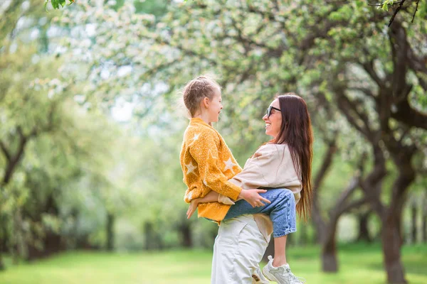 Family of mother and daughter in blooming cherry garden — Stock Photo, Image