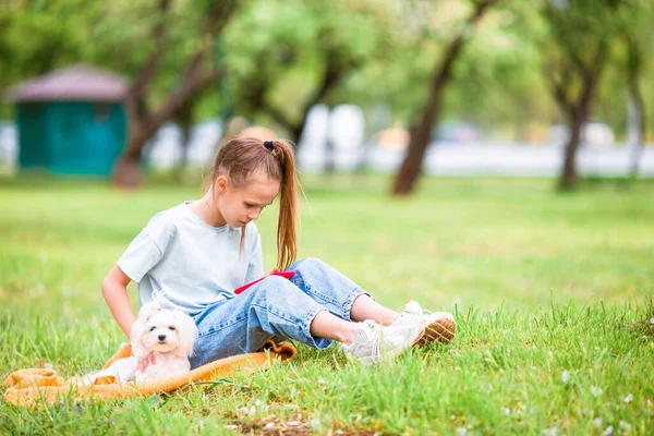 Little smiling girl playing and hugging puppy in the park — Stock Photo, Image