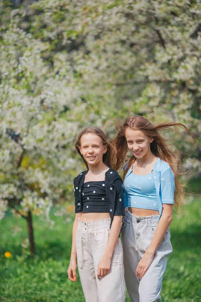 Urocze dziewczynki w kwitnącym ogrodzie jabłoni w wiosenny dzień — Zdjęcie stockowe