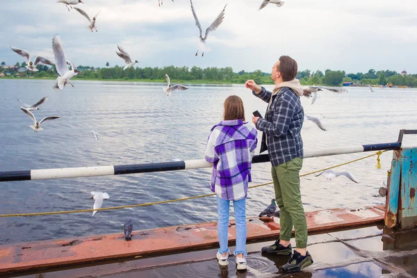 Gelukkig vader en klein meisje voeden meeuwen — Stockfoto