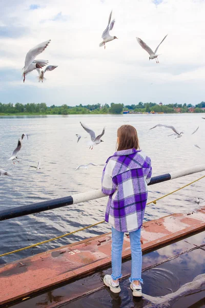 Cute little girl feed seagulls — Stock Photo, Image