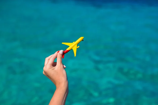 Small homemade plane in female hand on background of the sea — Stock Photo, Image