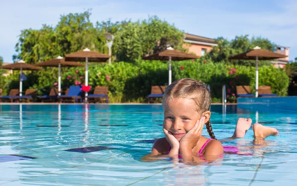 Linda niña feliz en la piscina mirando a la cámara — Foto de Stock