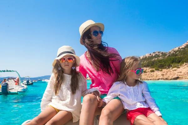 Young mother with her adorable daughters resting on a big boat — Stock Photo, Image