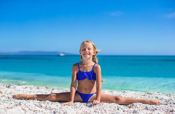 Adorable little girl making leg-split on tropical white sandy beach and enjoying summer vacation — Stock Photo, Image