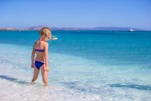 Bedårande liten flicka i grunt vatten ha roligt på vita stranden — Stockfoto