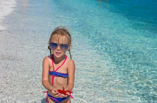 Petite adorable fille avec étoile de mer à la plage tropicale — Photo