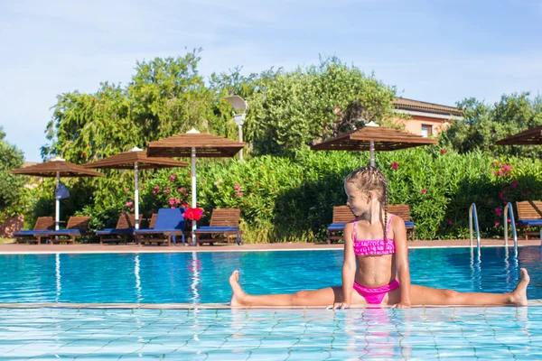 Schattig gelukkig meisje in het zwembad zittend op de splitsingen — Stockfoto