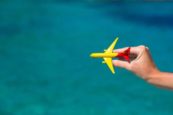 Malé domácí letadlo v ženské ruce na pozadí moře — Stock fotografie