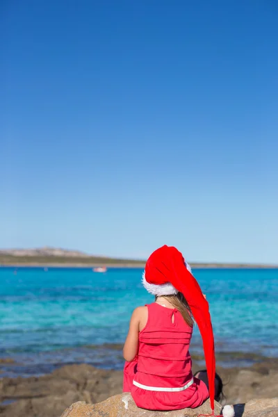 Vista posteriore di adorabile bambina a Babbo Natale cappello su grande pietra — Foto Stock