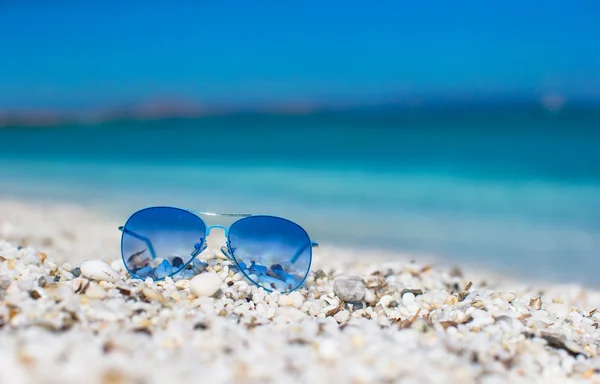 Close up van kleurrijke blauwe zonnebril op tropisch strand. — Stockfoto