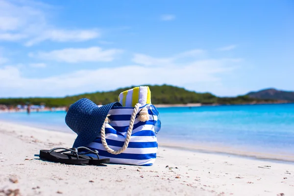 Chapéu de palha, saco, óculos de sol e toalha na praia tropical branca — Fotografia de Stock