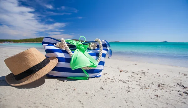 Summer accessories, swimsuit, sun glasses, bag and hat on white beach