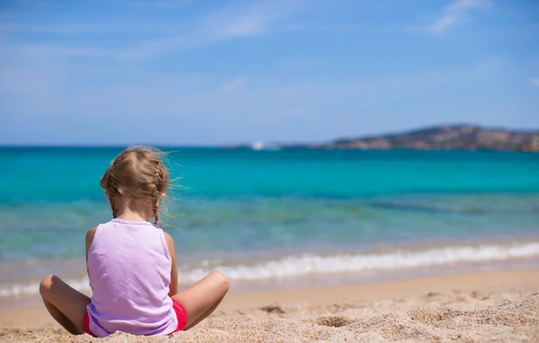Красивая маленькая девочка играет с песком на белом пляже — стоковое фото