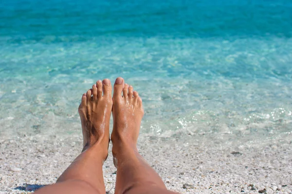 Closeup of female legs background of the turquoise sea — Stock Photo, Image